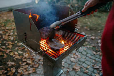 Cropped image of man preparing food on barbecue grill in yard