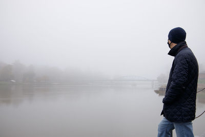 Rear view of man standing against lake