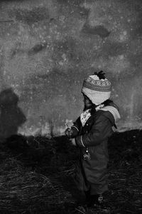 Girl standing on field against retaining wall