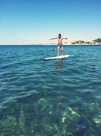 Man surfing on sea against clear sky