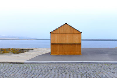 Beach hut by sea against clear sky