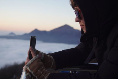 Midsection of man using mobile phone at sunset