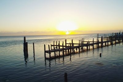 Pier over sea against sky during sunrise