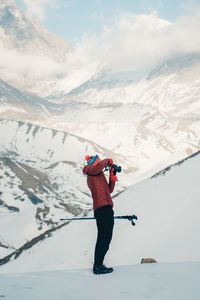 Rear view of woman standing on snowcapped mountain