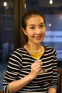 Portrait of a smiling young woman holding drink