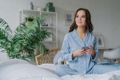 Portrait of young woman sitting on bed at home