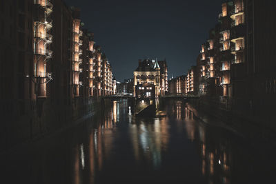 Canal amidst illuminated buildings in city at night