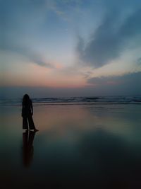 Silhouette man standing on beach against sky during sunset