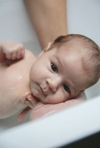 Cropped hands of mother bathing baby girl in bathtub