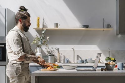 Young man preparing food on table at home