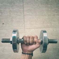 Cropped hand lifting dumbbell on floor