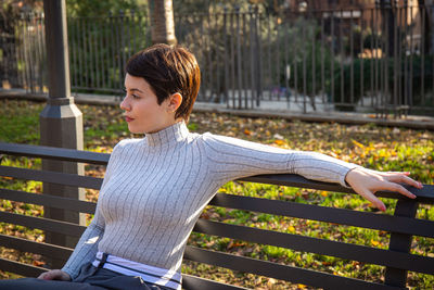 The young woman is sitting on a park bench in rome. 