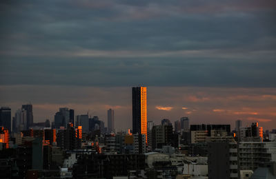 Modern buildings in city against cloudy sky during sunset