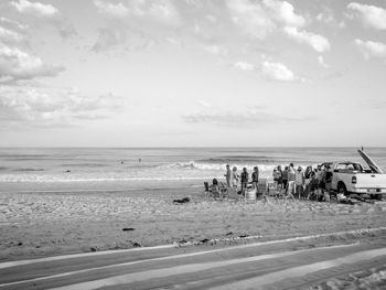 Group of people on beach against sky