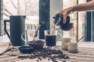 Cropped hand of woman holding coffee on table