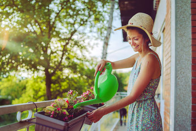 Woman wearing hat standing against plants