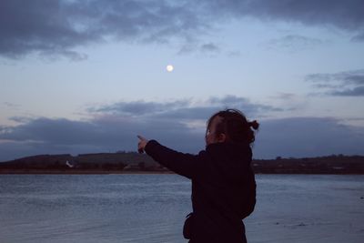 Girl pointing while standing at beach