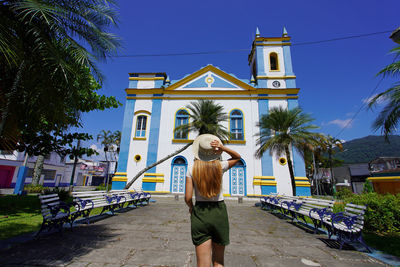 Young tourist woman in front of the church igreja matriz in the historic center of ubatuba, brazil.