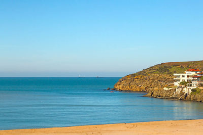 Scenic view of beach against clear blue sky on sunny day