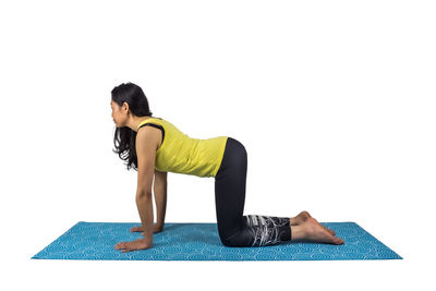Side view of woman sitting against white background