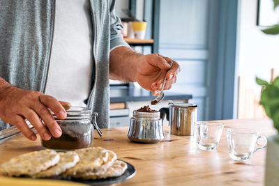 Man preparing classic italian coffee in the mocha, filling funnel of a moka pot with ground coffee. 