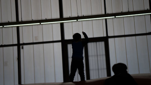 Rear view of silhouette people standing against window