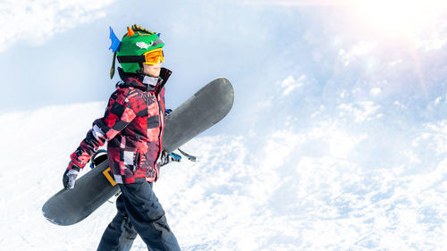 Side view of boy walking in snow during winter