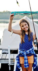 Portrait of happy girl caught fish at harbor