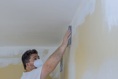 Portrait of man standing against wall at home