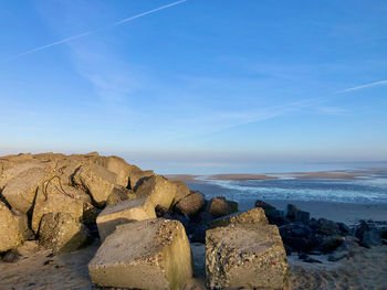 Rocks on beach against blue sky