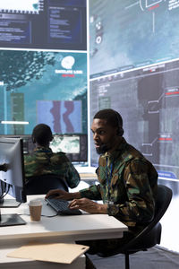 Side view of man using laptop at office