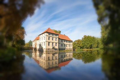 Buildings by lake against sky