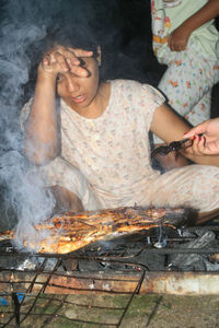 Low angle view of woman preparing food on barbecue grill