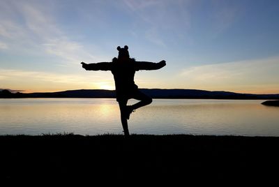 Silhouette man standing on beach against sky during sunset