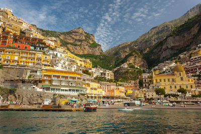 Low angle view of houses on mountain by sea against sky