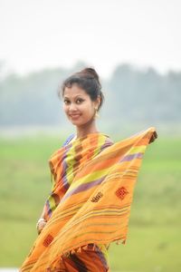 Portrait of smiling young woman standing on field