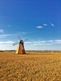 Windmill on field against blue sky