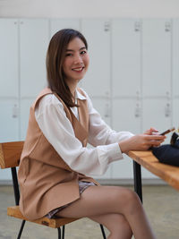 Portrait of smiling young woman sitting at locker room