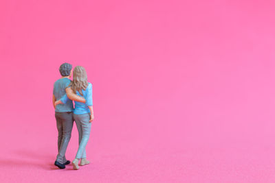 Rear view of man standing against pink background