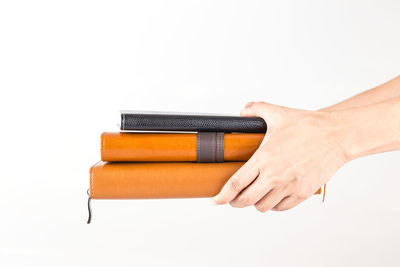 Close-up of hand holding book against white background