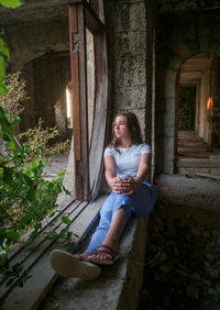 Teen girl sitting by the window in an abandoned building