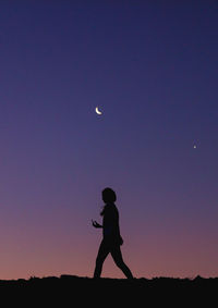 Silhouette man standing against moon in sky during sunset