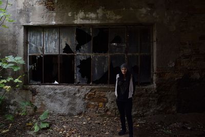 Woman standing against abandoned building