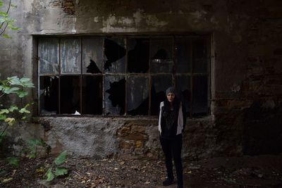 Portrait of young woman standing against wall