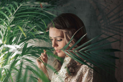 Woman with plant against wall