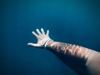 Cropped hand of person swimming in sea