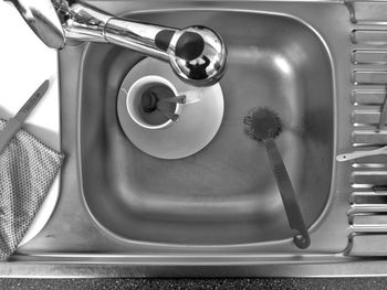 Directly above shot of cup and saucer with brush in sink