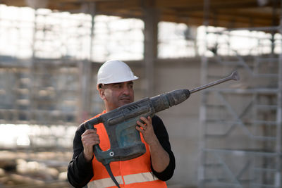 Worker holding drill at construction site