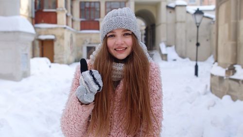 Portrait of young woman holding coffee cup while standing outdoors