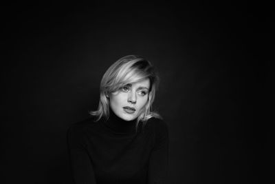 Portrait of a beautiful young woman over black background